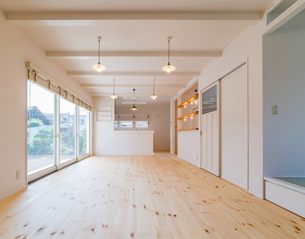 ホワイト塗装の天井、壁、建具と、幅広いパイン材の床が室内をぬくもりのある空間。